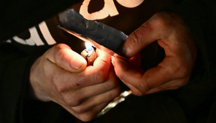 A photo of a person's hands holding a lighter under a piece of foil with fentanyl.