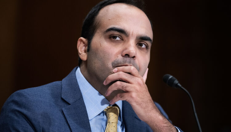 A photograph of Rohit Chopra during the senate hearing. He holds his chin in his left hand in a contemplative position.