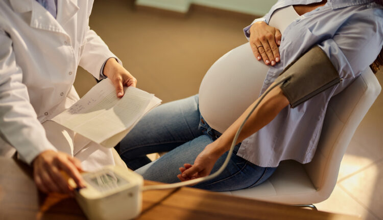 A photo of a pregnant woman having her blood pressure measured by a doctor.